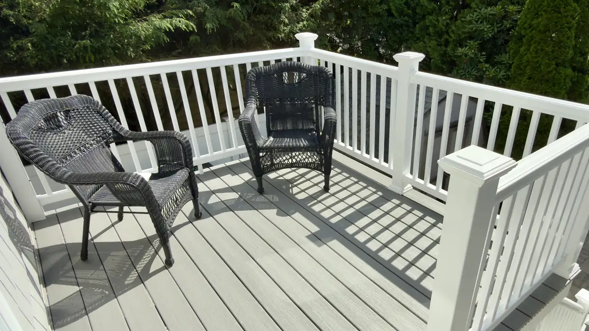 Composite deck with gray boards and white railing, furnished with two chairs